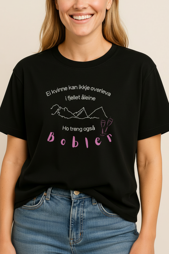 Ei dame med svart t-skjorte med prosecco design med trykk av bobler og fjell. Ei kvinne kan ikkje overleva i fjellet åleine, ho treng også bobler