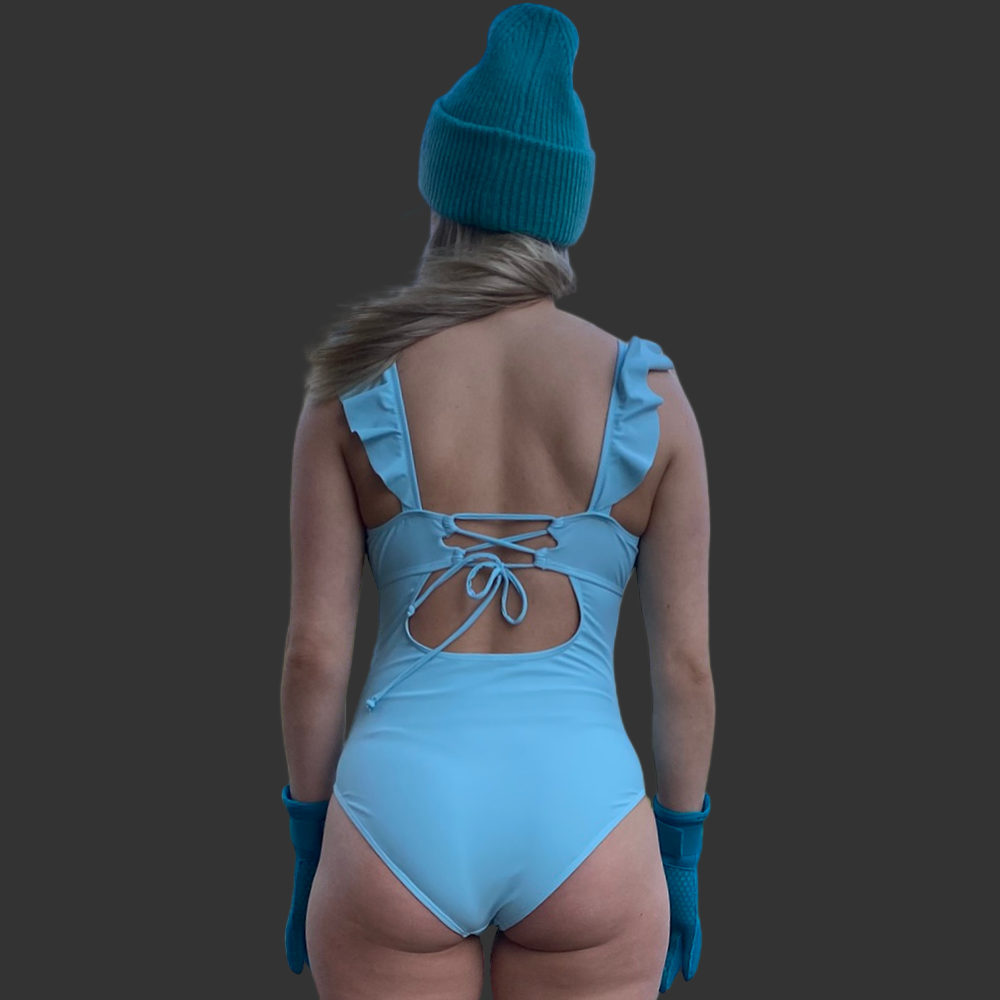 n dame som har på en himmelblå badeddrakt med volanger og snøring i ryggen som tilbehør turkis lue og neopren hansker