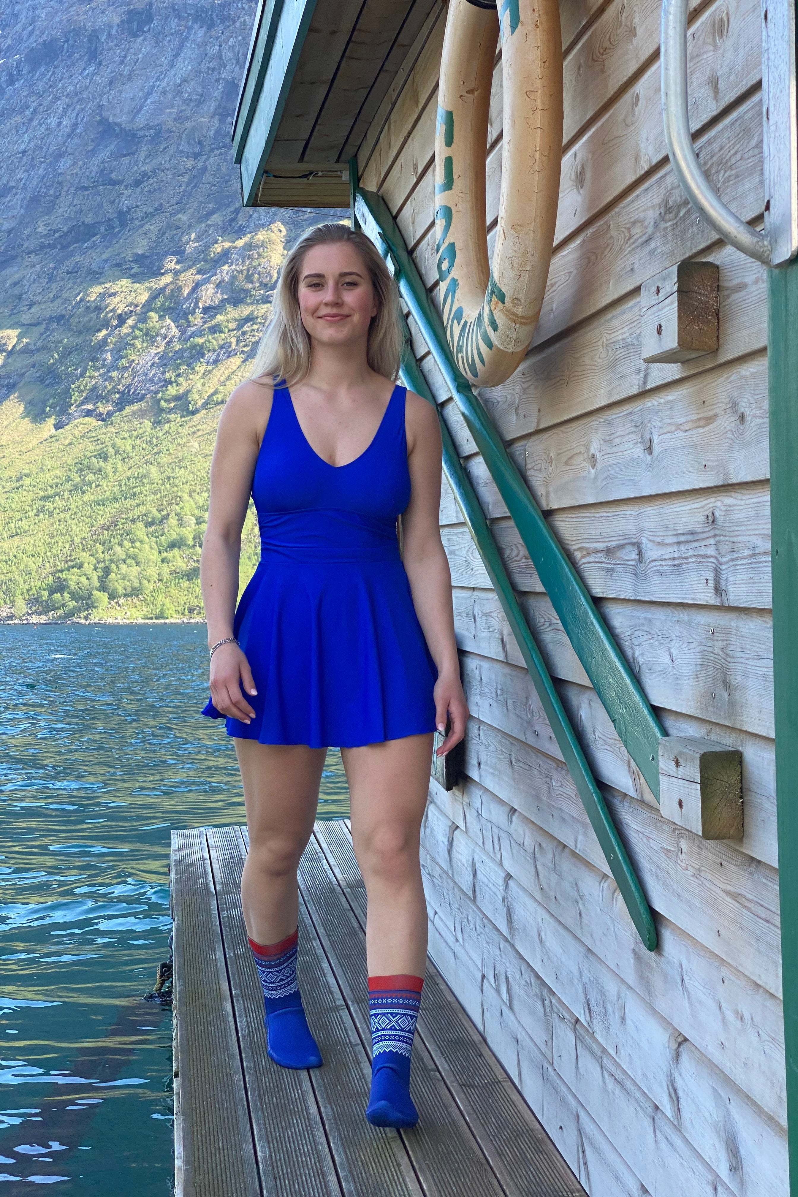 Marius® Originale Neoprene Socks - DoUdare dame som har på matchende blå kjole går på en brygge ved en norsk fjord