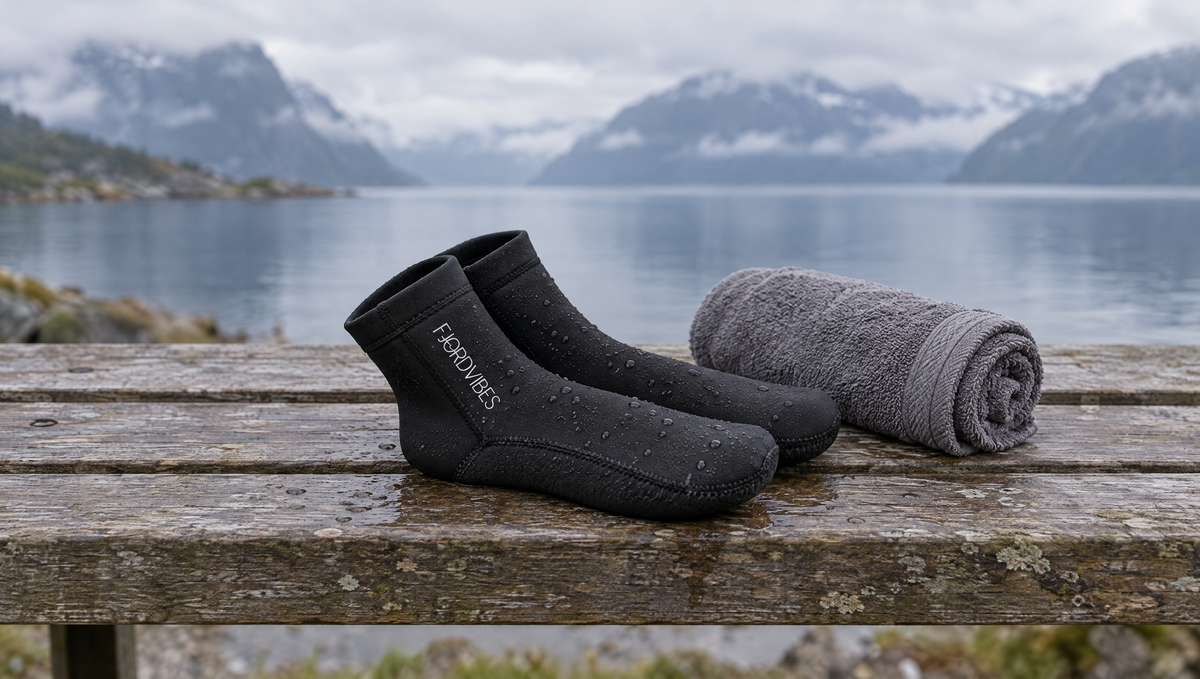 Svarte neoprensokker lagt til tørk på en benk ved fjorden
