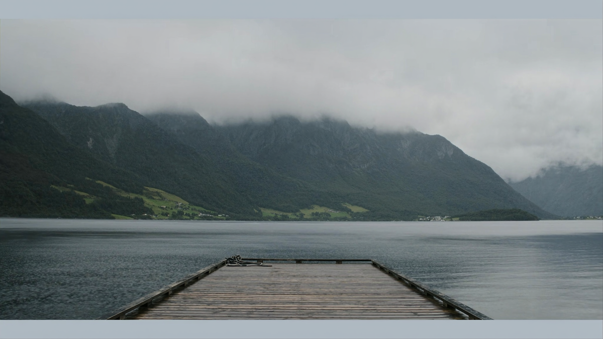 Stille fjord med svømmebrygge i tåke og lett regn