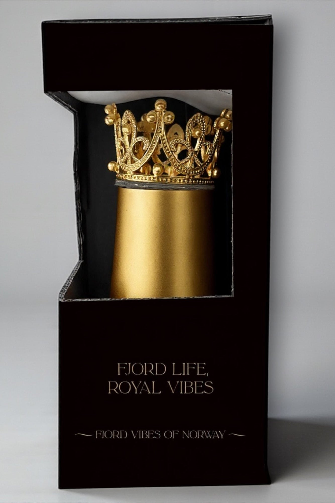 Bilde av en svart, elegant eske med vindu der en ser en prosecco kopp i gull med gull-krone inni. Av Fjord Vibes of Norway
