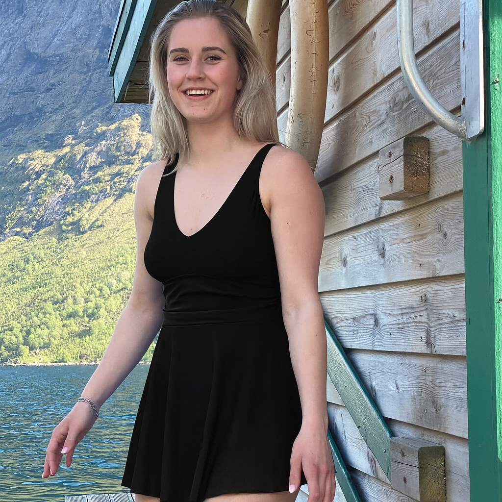 Dame som har på svart marilyn badekjole fra Fjord Vibes of Norway og såt på en brygge ved en flytende sauna i en norsk fjord